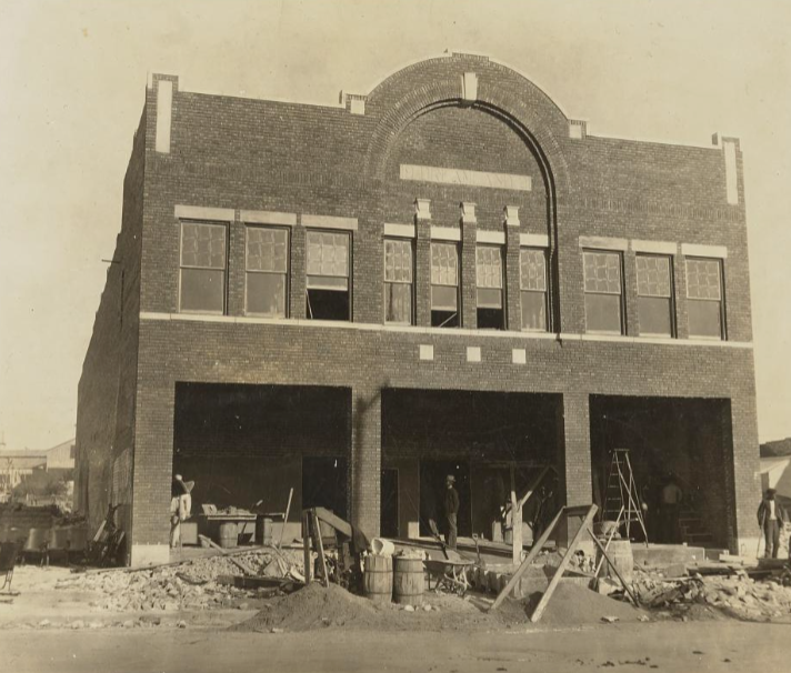 Archival photograph of the Dreamland building under reconstruction in Greenwood, with workers and building materials in front of the brick storefront