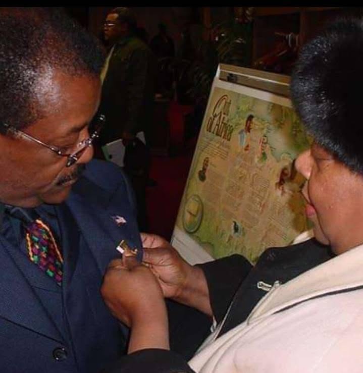 Princetta Newman pinning a Black Wall Street lapel pin on attorney Johnnie Cochran at a Tulsa event