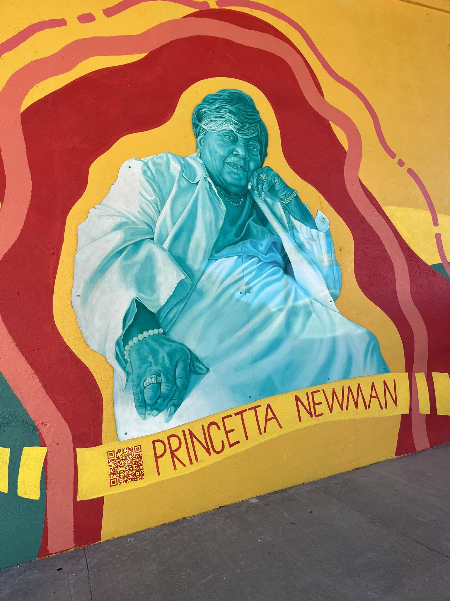 Public mural portrait of Princetta Newman painted in teal against a red and yellow background, with her name and a QR code
